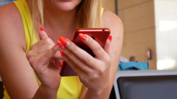 Молодая пассажирка пользуется красным смартфоном в аэропорту — стоковое видео