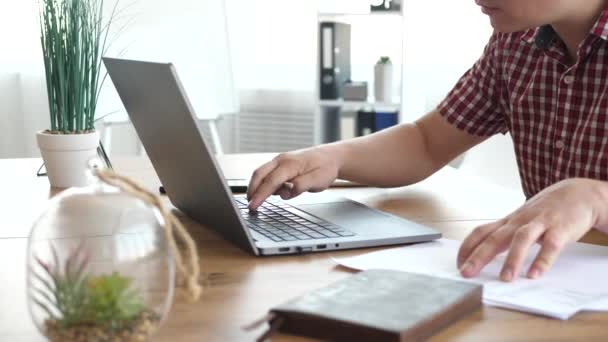 Homem trabalha com documentos de papel usando laptop — Vídeo de Stock