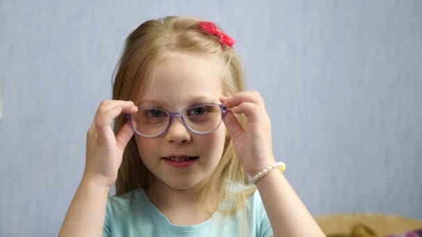 Niña linda se quita las gafas en casa en la habitación — Vídeo de stock