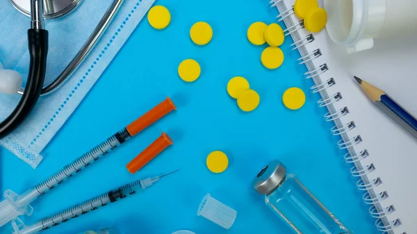 Syringe for Insection, Yellow tablets and Stethoscope As Background