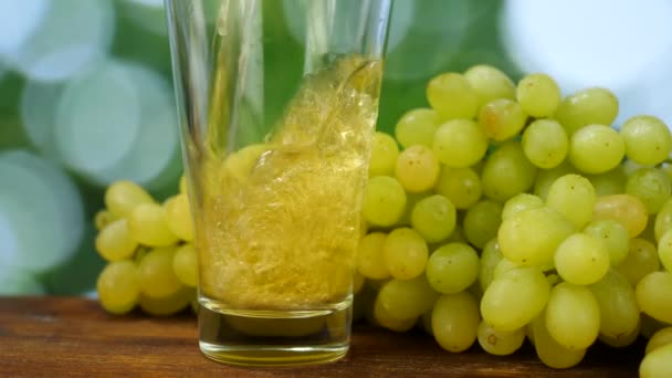 El jugo orgánico crudo se vierte en un vaso de vidrio con fondo de uvas blancas maduras — Vídeo de stock