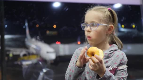 Linda niña come manzana en el aeropuerto en el fondo del avión por la noche — Vídeo de stock