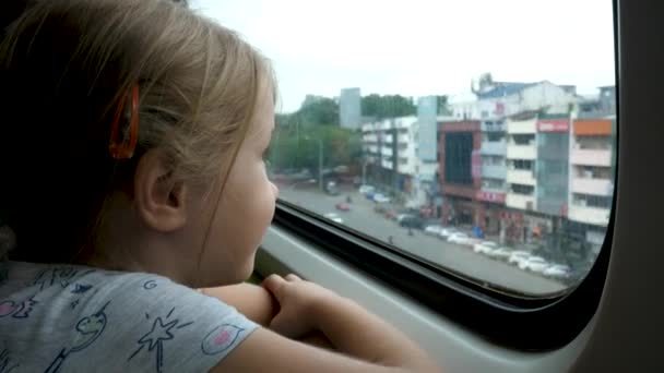 Küçük kız yolculuk sırasında vagondaki trenin camından dışarı bakar. — Stok video