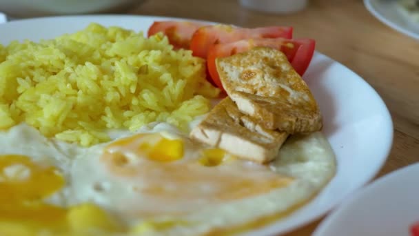 Соевый соус кладут на тофу или бобовый творог с куркумой риса, помидоров и жареных куриных яиц — стоковое видео