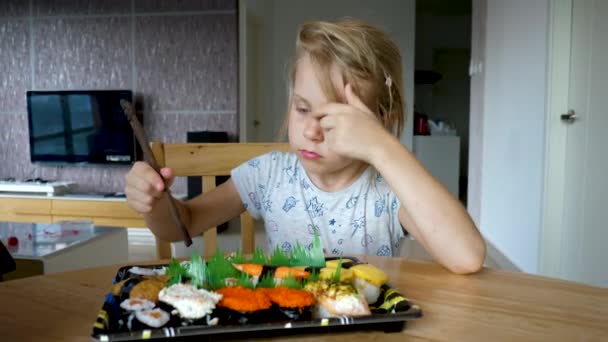 Liten flicka sniffa och välja variation rad av inslagna rullar sushi — Stockvideo