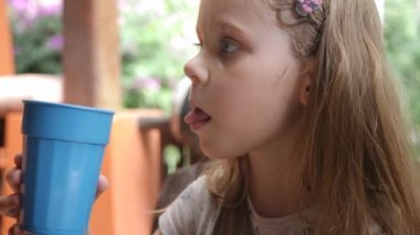Cute Child Drinks Water with Blue Plastic Glass