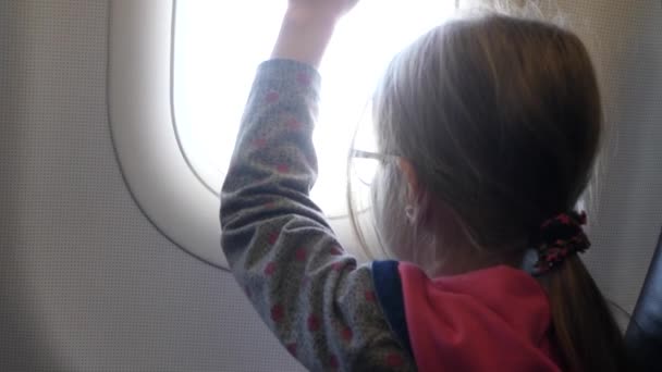 Little Girl Closes and Opens Window in Airplane — Stockvideo