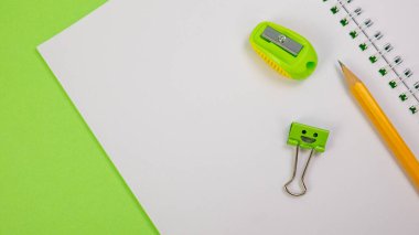 School Notepad with Pencil Pointer, Yellow Pencil and Smile Binder Clip on Green Background