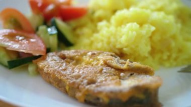 Fresh sliced tomato and cucumber slices with fried fish on white plate