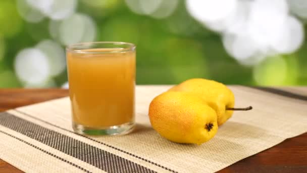 Грушевый сок в стекле и фрукты на столе на зеленом фоне — стоковое видео