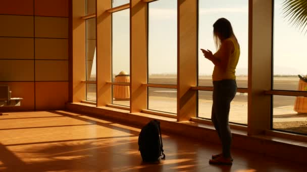 Silhouette of tourist woman uses smartphone in airport — 图库视频影像