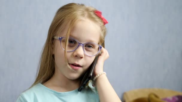 Happy little girl calls on smartphone at home — Stok video