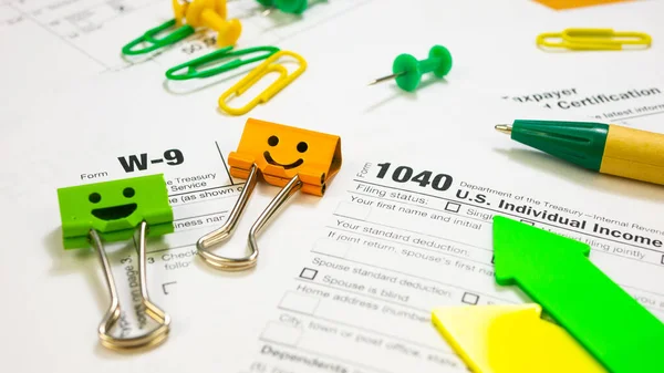 Smile Orange and Green Binder Clips with Pen on 1040 Tax Form and W-9 — ストック写真