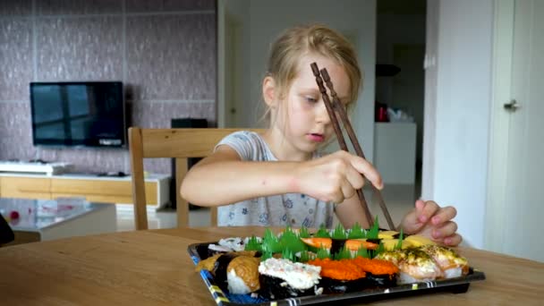 Молодая девушка пытается берет суши роллы подается на тарелку — стоковое видео