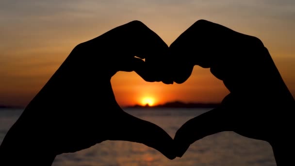 Silueta prstů ve tvaru srdce na dramatickém západu slunce — Stock video