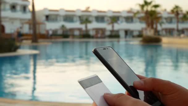 Comprar en línea con teléfono inteligente y tarjeta de crédito cerca de piscina — Vídeo de stock