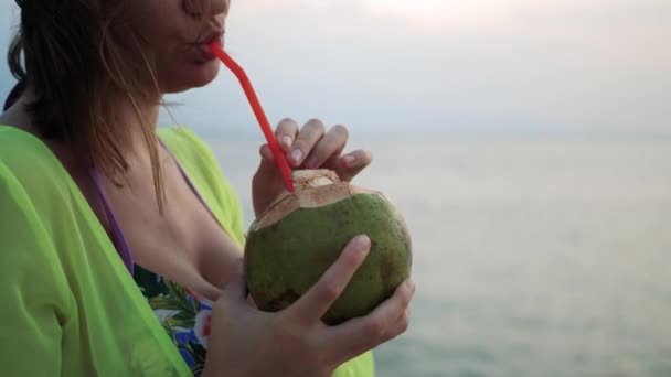 청소하는 여자 가 바다 경치를 즐기고 밀짚 에서 신선 한 코온 우트 밀크를 마시는 모습 — 비디오