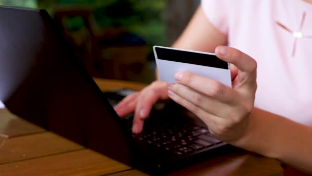 Manos femeninas sosteniendo la tarjeta de crédito y usando el ordenador portátil negro — Vídeos de Stock