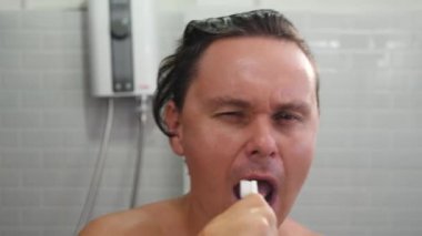 Adam dişlerini gökkuşağı bambu diş fırçasıyla fırçalıyor.