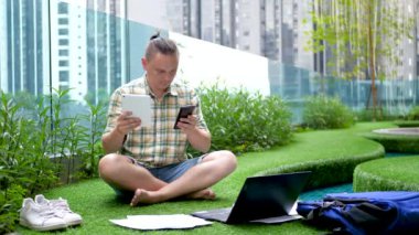 Yakışıklı erkek bilişim programcısı akıllı telefon, tablet bilgisayar ve laptop kullanıyor