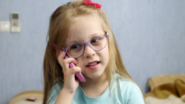 Дитяча дівчинка в окулярах розмовляє телефоном — стокове відео