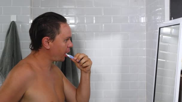 Banyoda dişlerini fırçalayan yakışıklı erkek. — Stok video