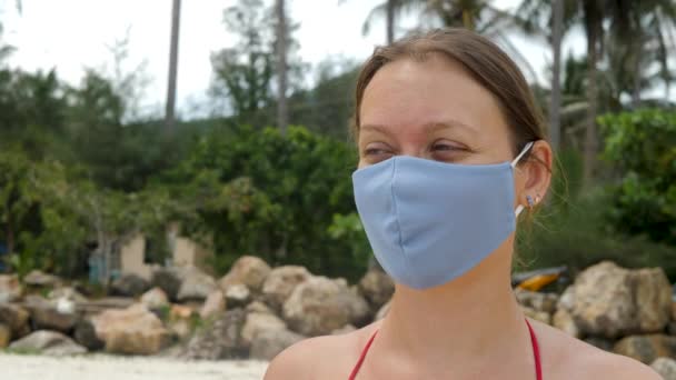 Mujer en tela mascarilla en el fondo de la palmera — Vídeo de stock