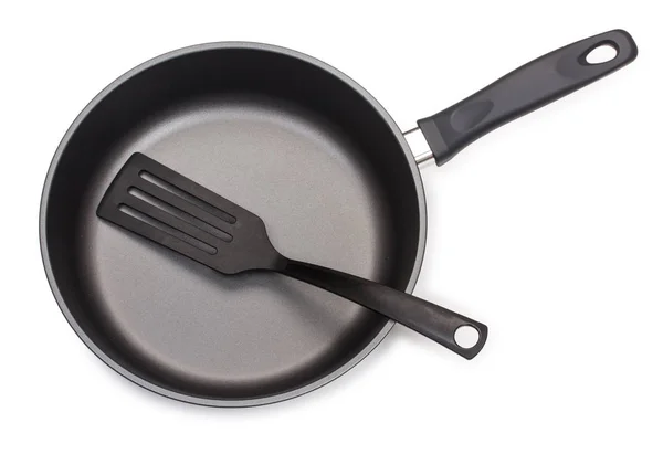Sartén negra con utensilios de cocina: paleta de plástico, aislada —  Fotos de Stock