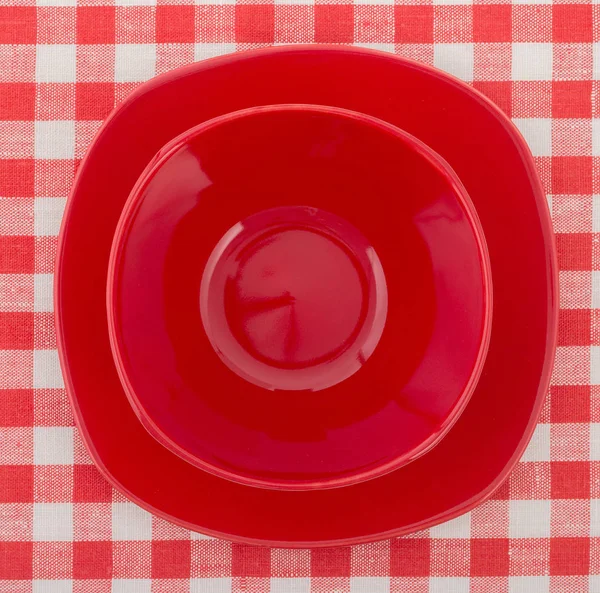 Conjunto de elegante plato rojo y un tazón en la mesa a cuadros blanco-rojo — Foto de Stock