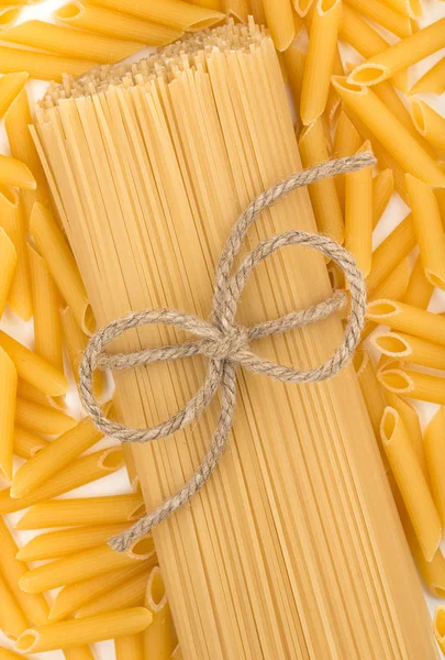 Un mazzo di spaghetti con fiocco di corda su uno sfondo di pasta. Chiudere — Foto Stock