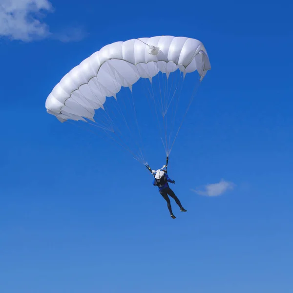 Mavi arka planda beyaz paraşütlü bir paraşütçü.. — Stok fotoğraf