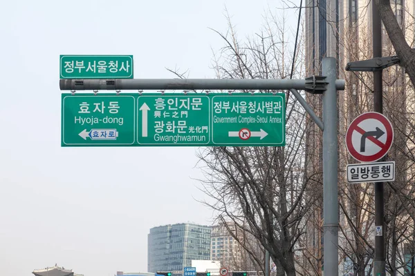 Poste de señal de dirección múltiple con nombres de ciudad en Inglés y Kore —  Fotos de Stock