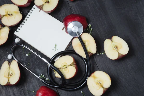 Appels, een boek en een stethoscoop op een zwarte achtergrond in concept van — Stockfoto