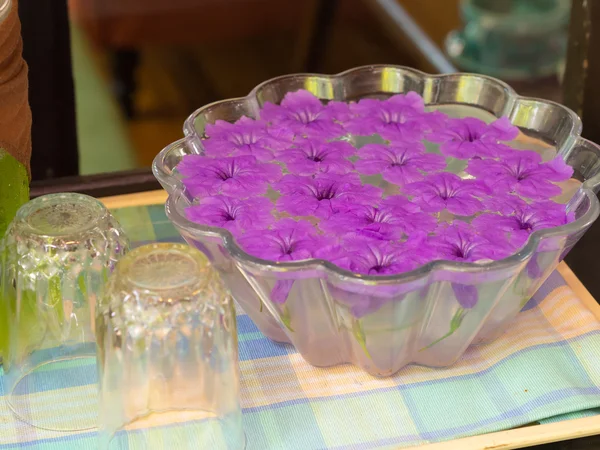 Flores púrpuras flotando en frasco de vidrio. sobre una mesa de madera . — Foto de Stock