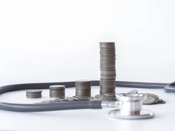 Стетоскоп і монета стоять на білому тлі. гроші на охорону здоров'я, фінансова допомога, концепція . — стокове фото