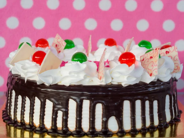 Chokladtårta med vispgrädde på rosa bakgrund. — Stockfoto