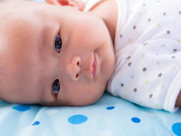 Primer plano, asiático recién nacido bebé sonriendo en cerulean color colchón  . — Foto de Stock