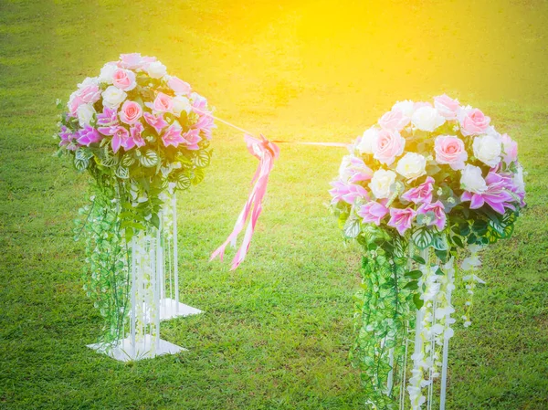 Ramo de flores artificiales en el césped. Enlace junto con una cinta y un lazo en el centro. Ceremonia de apertura y concepto de boda . — Foto de Stock