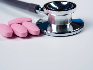 Beyaz arka plan üzerinde closeup, stetoskop ve pembe hap.