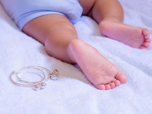 Baby feet on White cloth. and Anklets made of silver. — Stock Photo, Image