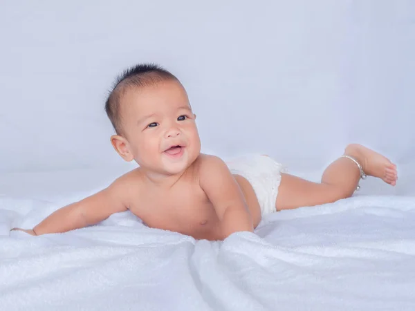 Azjatycka niemowlę leżeć na brzuchu, nie noszą ubrań, na białym obrusem. — Zdjęcie stockowe