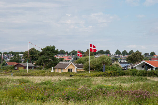 Летние дома и датский флаг перед домом для отдыха в Карре
