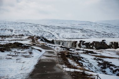 Karlı bir kış gününde Godafoss şelalesine giden yol