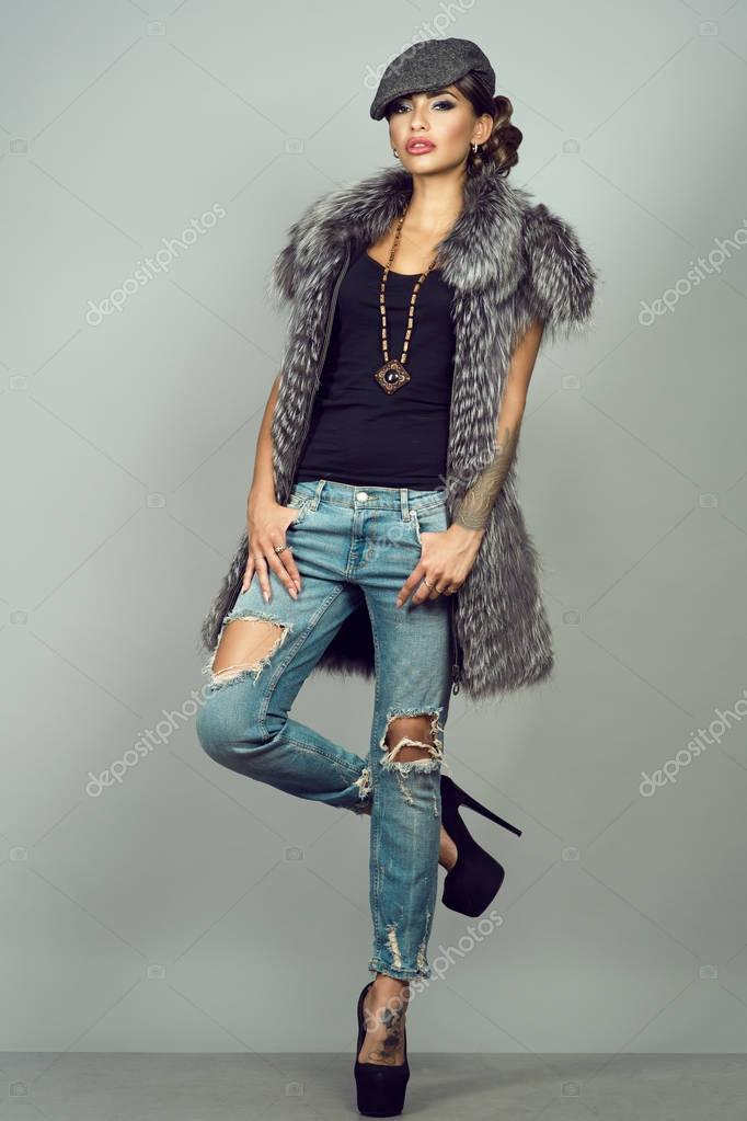 Portrait d\u0027une belle glam tatoué modèle avec porter veste de renard argenté maquillage provocateur, déchiré bleu jeans, chaussures à talons et chapeau