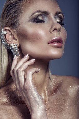 Şık muhteşem sarışın kadınla portre saç ıslak ve sanatsal pırıltılı makyaj kulağı ile üzerinde manşet dokunmadan gözlerini kapat ve dolgun dudaklar ayırdı.