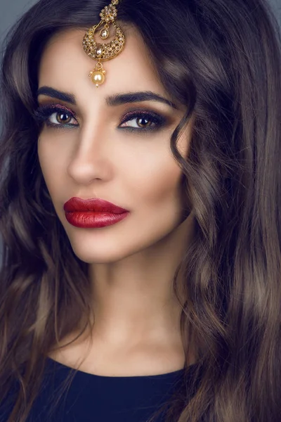 Retrato de linda jovem morena com cabelos longos e maquiagem provocante vestindo preciosos acessórios de cabelo nupcial indiano feitos de ouro e purl — Fotografia de Stock