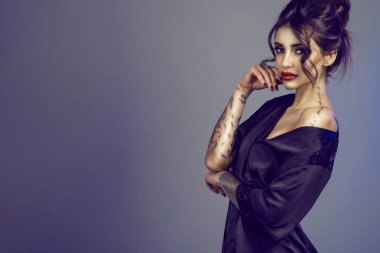 Baştan çıkarıcı genç portresi omzunun düşen siyah ipek sabahlığı giyen kışkırtıcı makyaj ve kabarık saçlı esmer modeli dövme