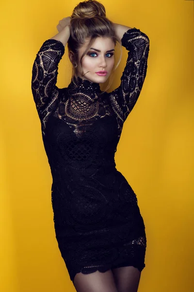 Портрет великолепной молодой глэм леди с прической updo носить обтягивающие короткие черные кружева платье и чулки. Изолированный на ярко-желтом фоне . — стоковое фото