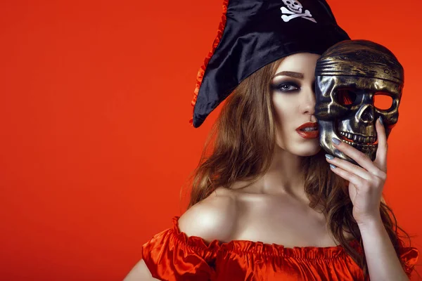 Portrait de magnifique femme sexy avec un maquillage provocateur en costume de pirate cachant la moitié de son visage derrière le masque de crâne — Photo