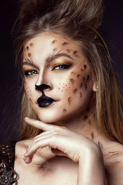 Retrato de cerca de la joven hermosa modelo de ojos grises con maquillaje artístico de leopardo y pelo cepillado mirando directamente a la cámara con el dedo debajo de la barbilla . — Foto de Stock